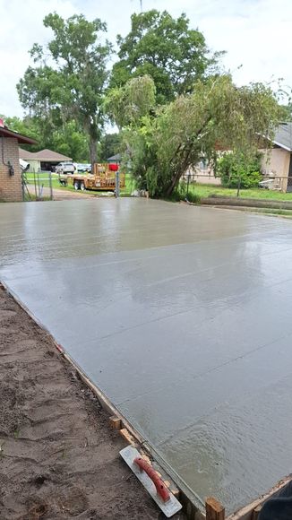 A person is laying concrete on a driveway with a trowel.