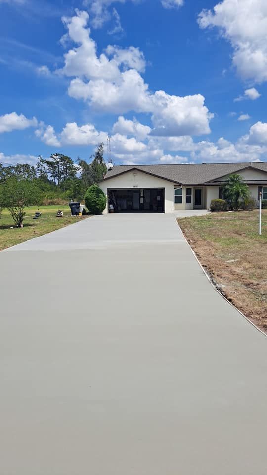 A concrete driveway leading to a house on a sunny day.