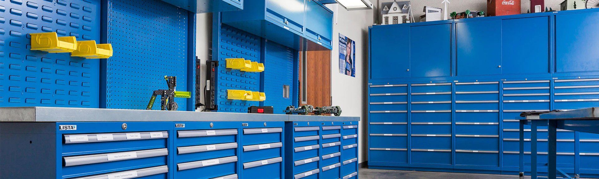 A garage with blue cabinets and drawers and a workbench.