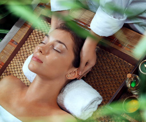 A woman is getting a head massage with her eyes closed