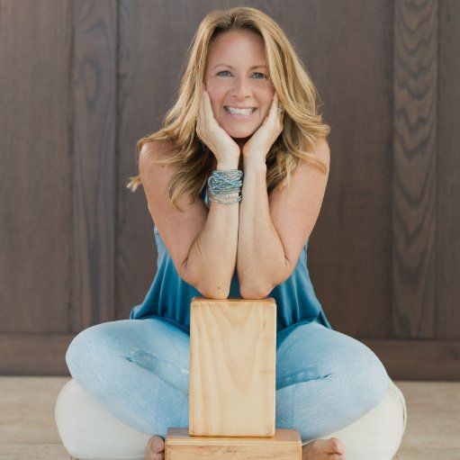 A woman is smiling while sitting on a wooden block