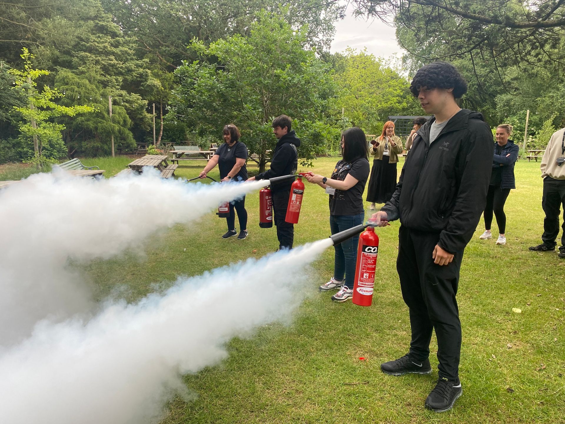 Two EMTs in yellow vests prepare a stretcher near an ambulance at night.