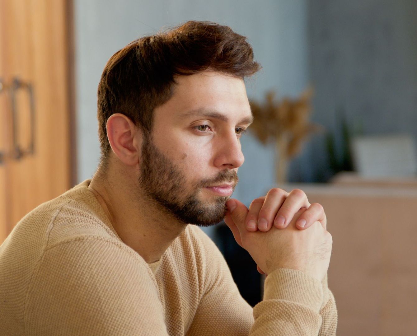 A woman is sitting on a couch with her head in her hands.