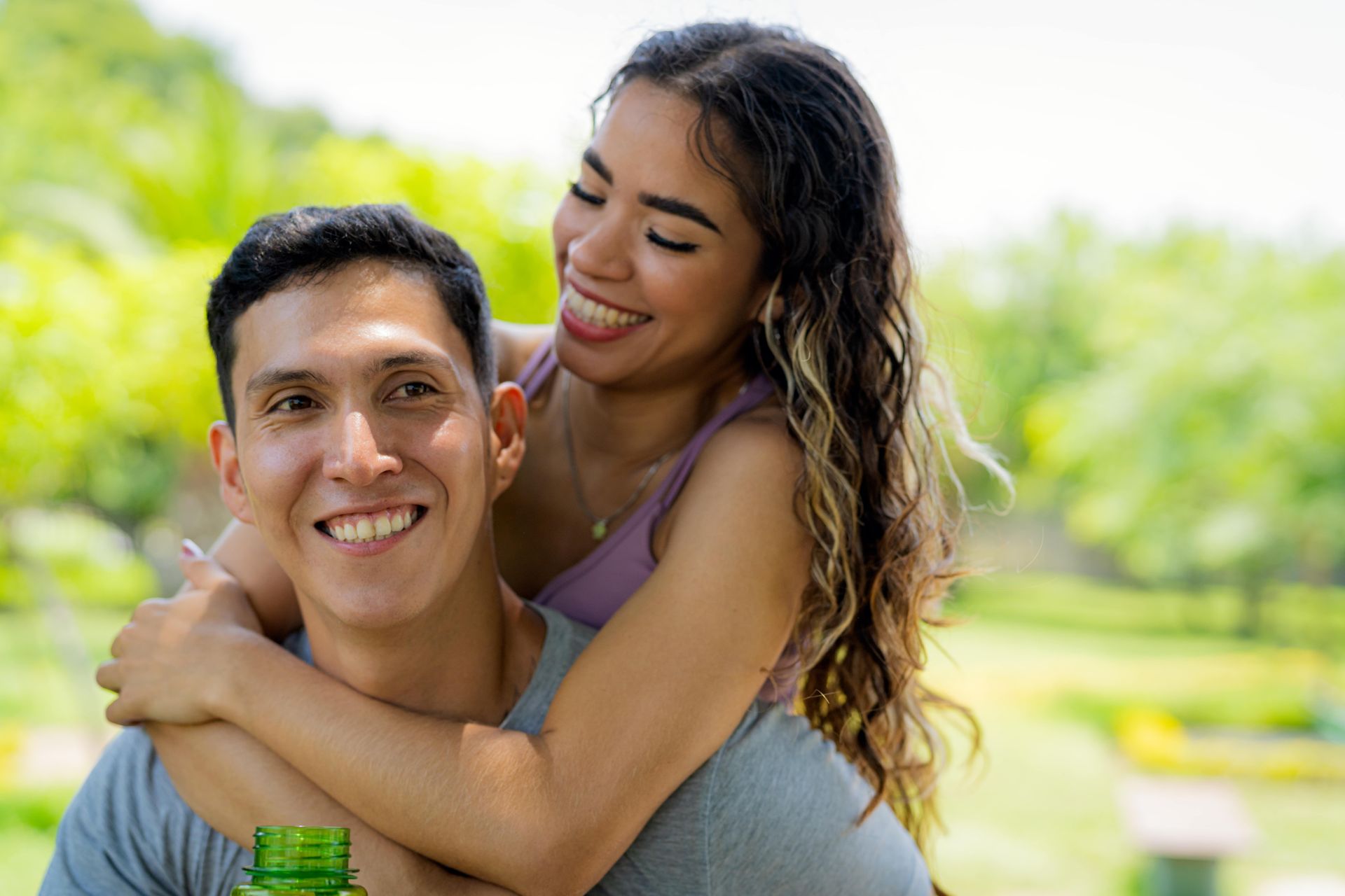 A man is carrying a woman on his back in a park.