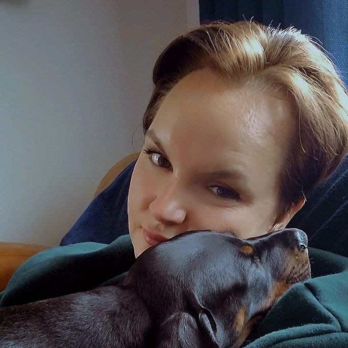 Miri, a member of the Charli's Pet Angels team, with her doberman puppy sleeping on her chest