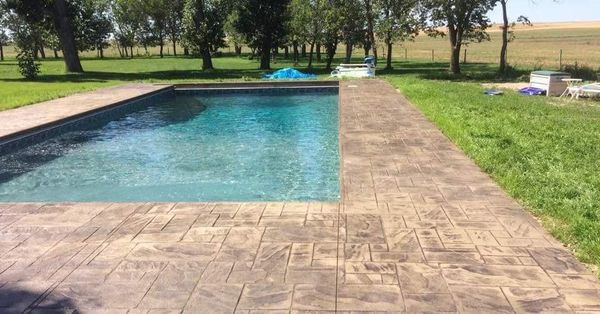 There is a large swimming pool in the middle of a lush green field.