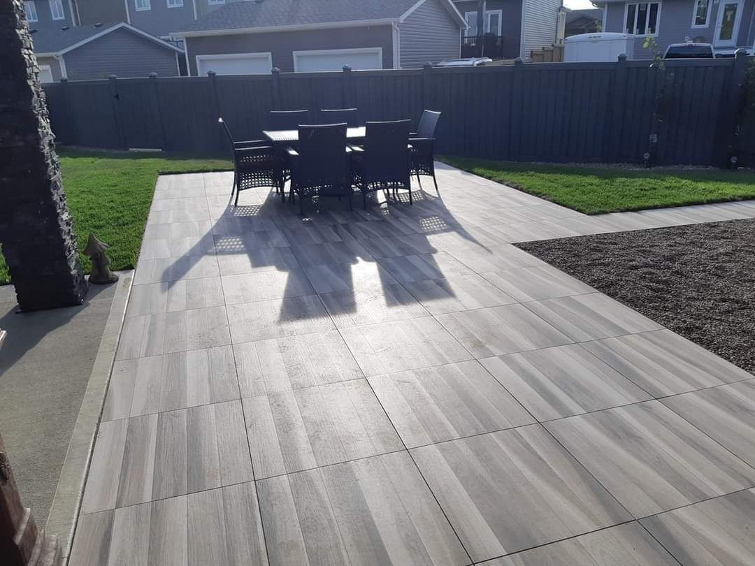 A patio with a table and chairs and a fence in the background.