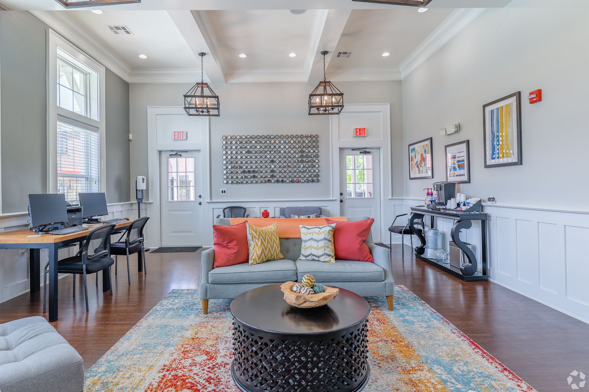 Cozy waiting room with gray walls, colorful rug, couch with pillows, coffee table, and desks.