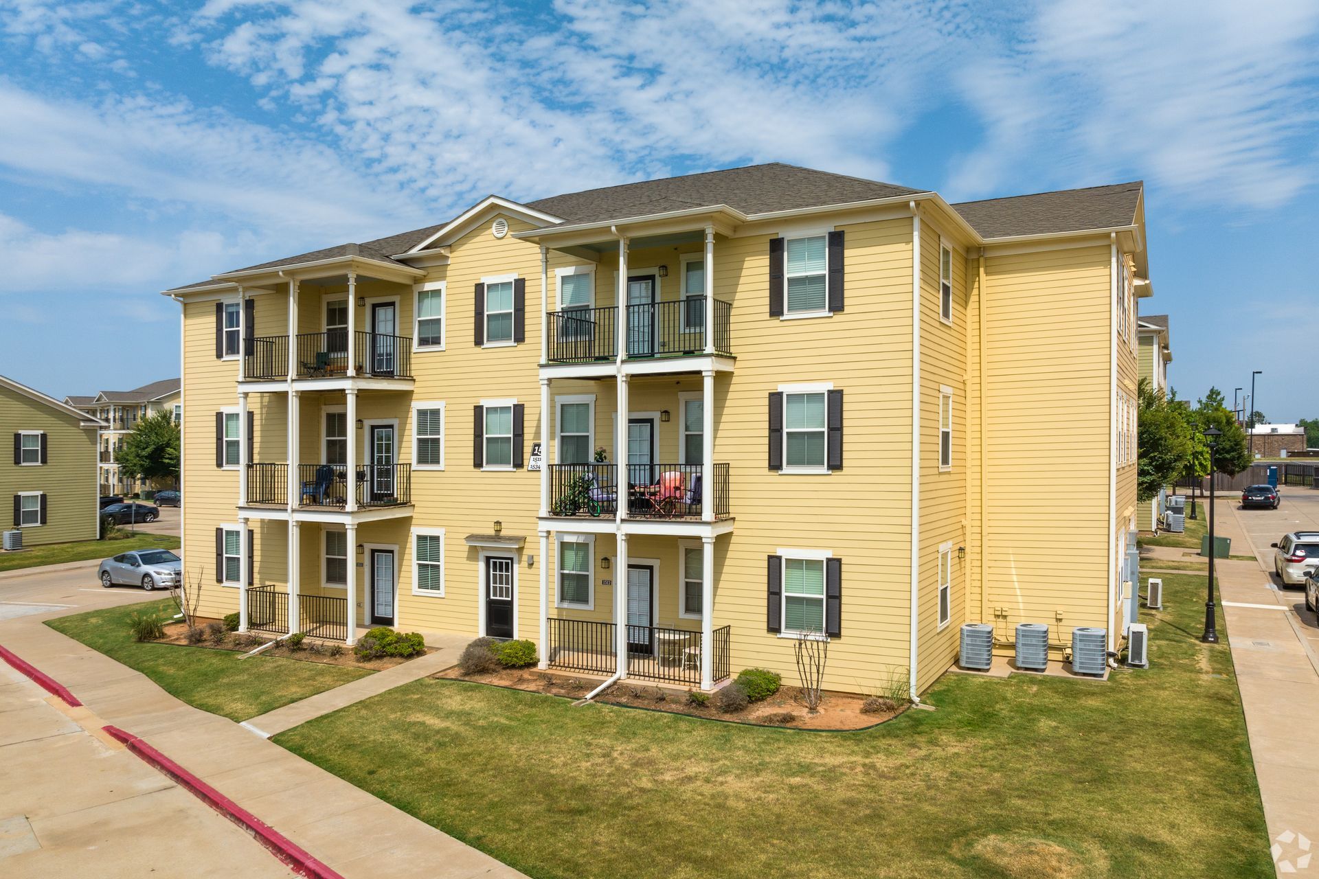 A large yellow apartment building with a lot of windows and balconies.