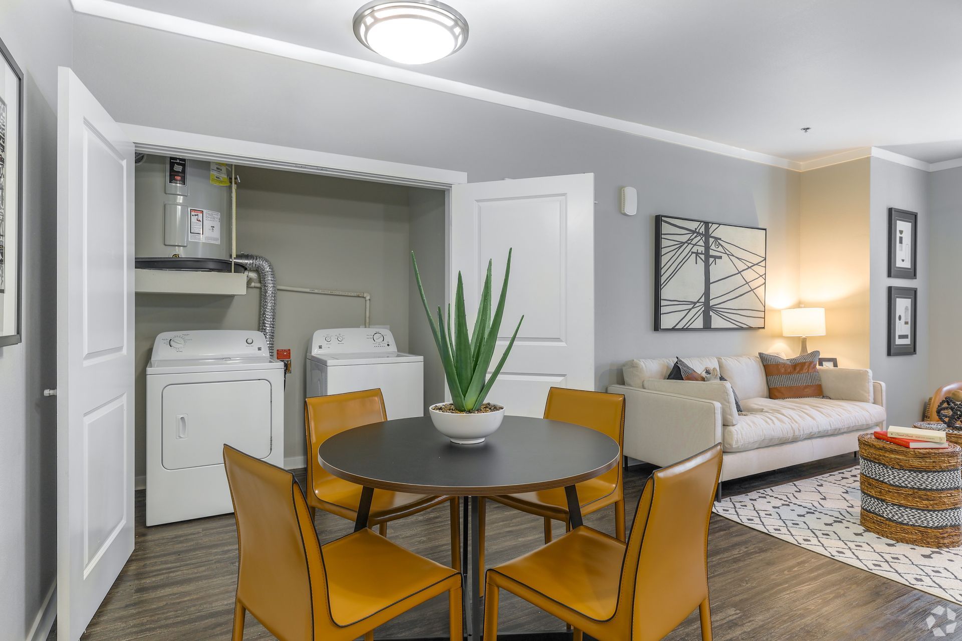 A living room with a dining table and chairs and a washer and dryer.