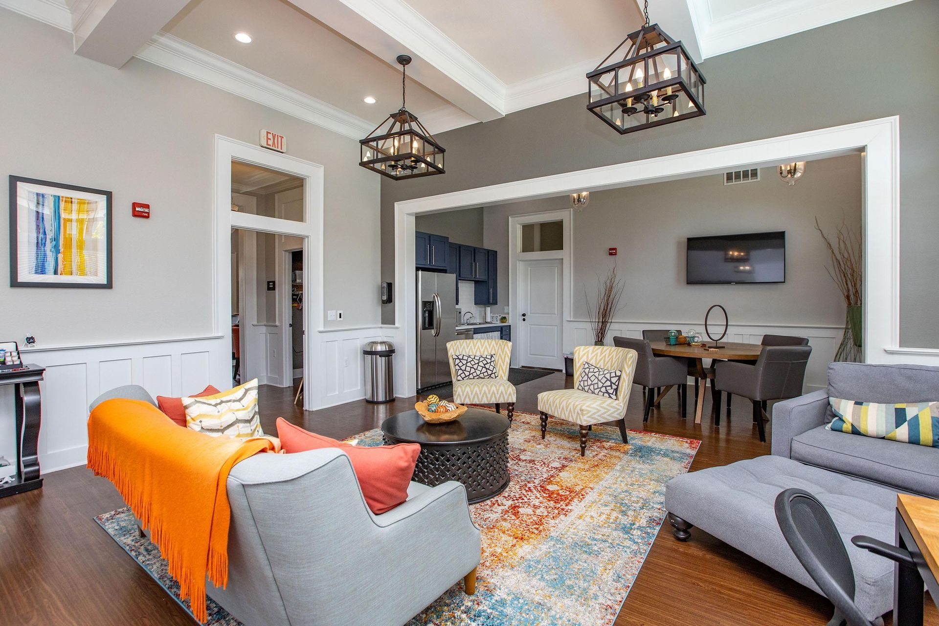 Living room with gray sofa, orange blanket, rug, dining area in background.