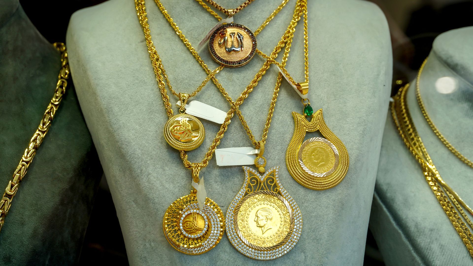 Gold necklaces with pendants on a display stand.