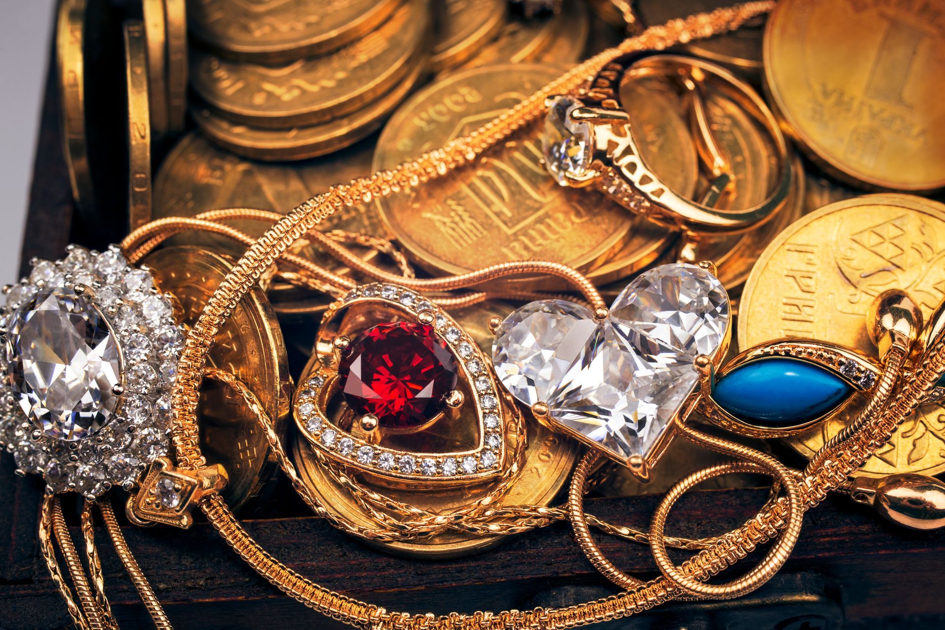 Close-up of a treasure chest overflowing with gold coins, necklaces, and rings with gemstones.