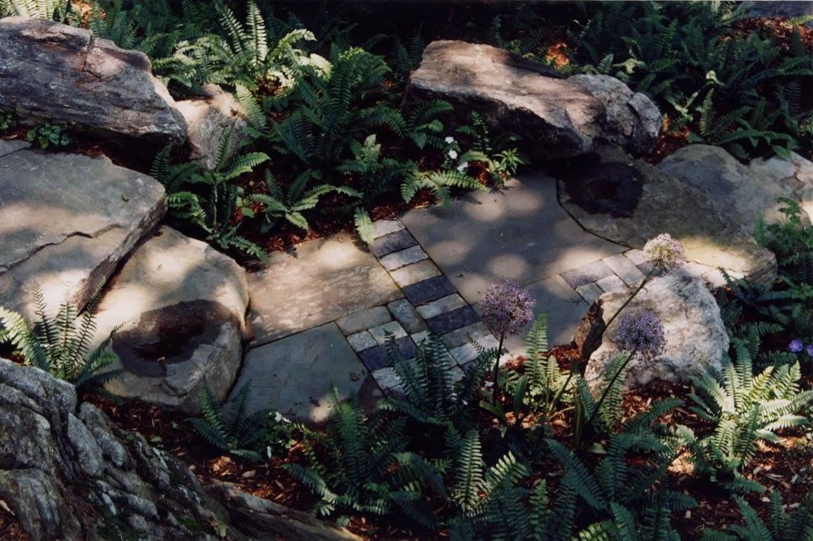 A stone walkway surrounded by plants and rocks in a garden