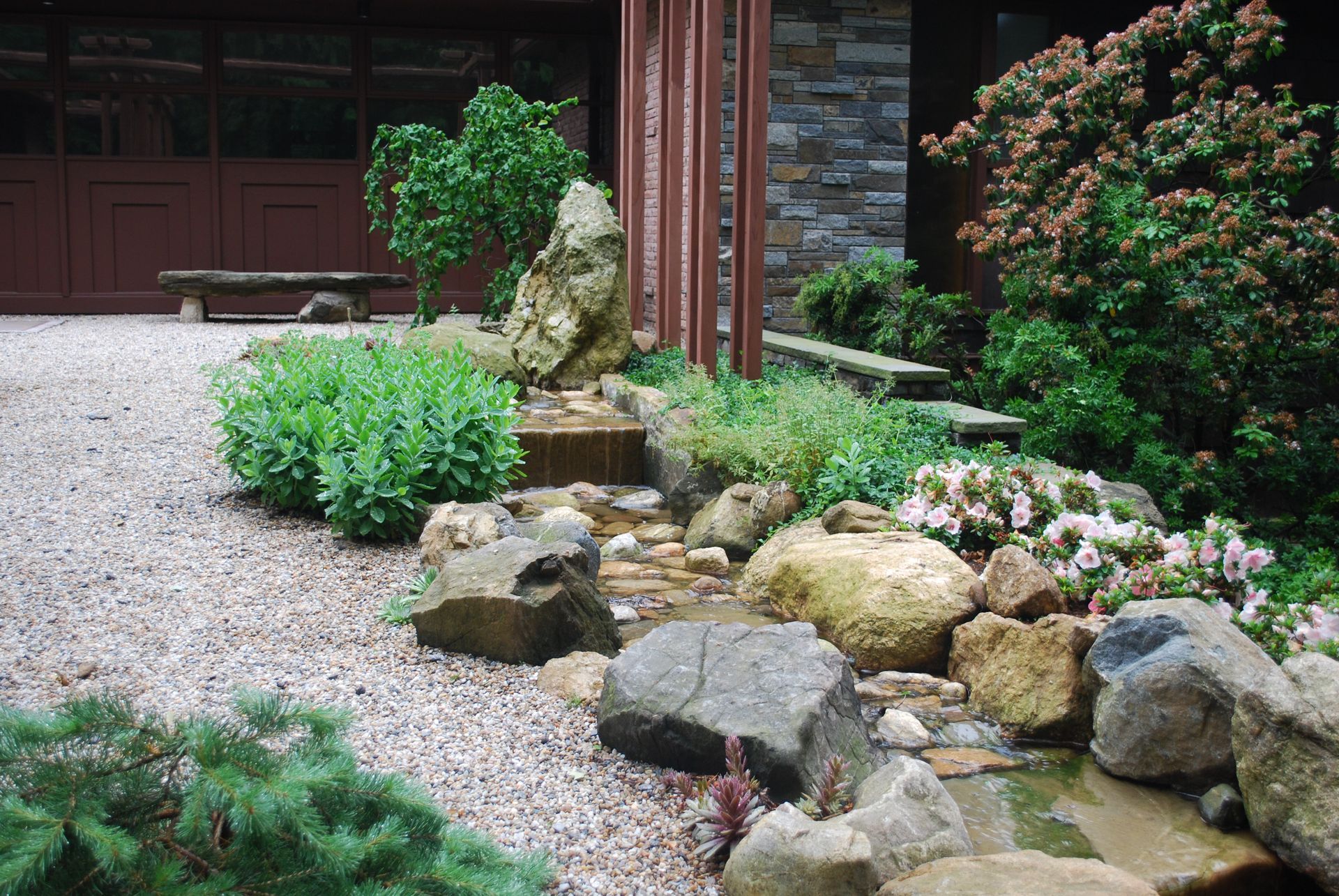 A garden with rocks and plants in front of a garage door