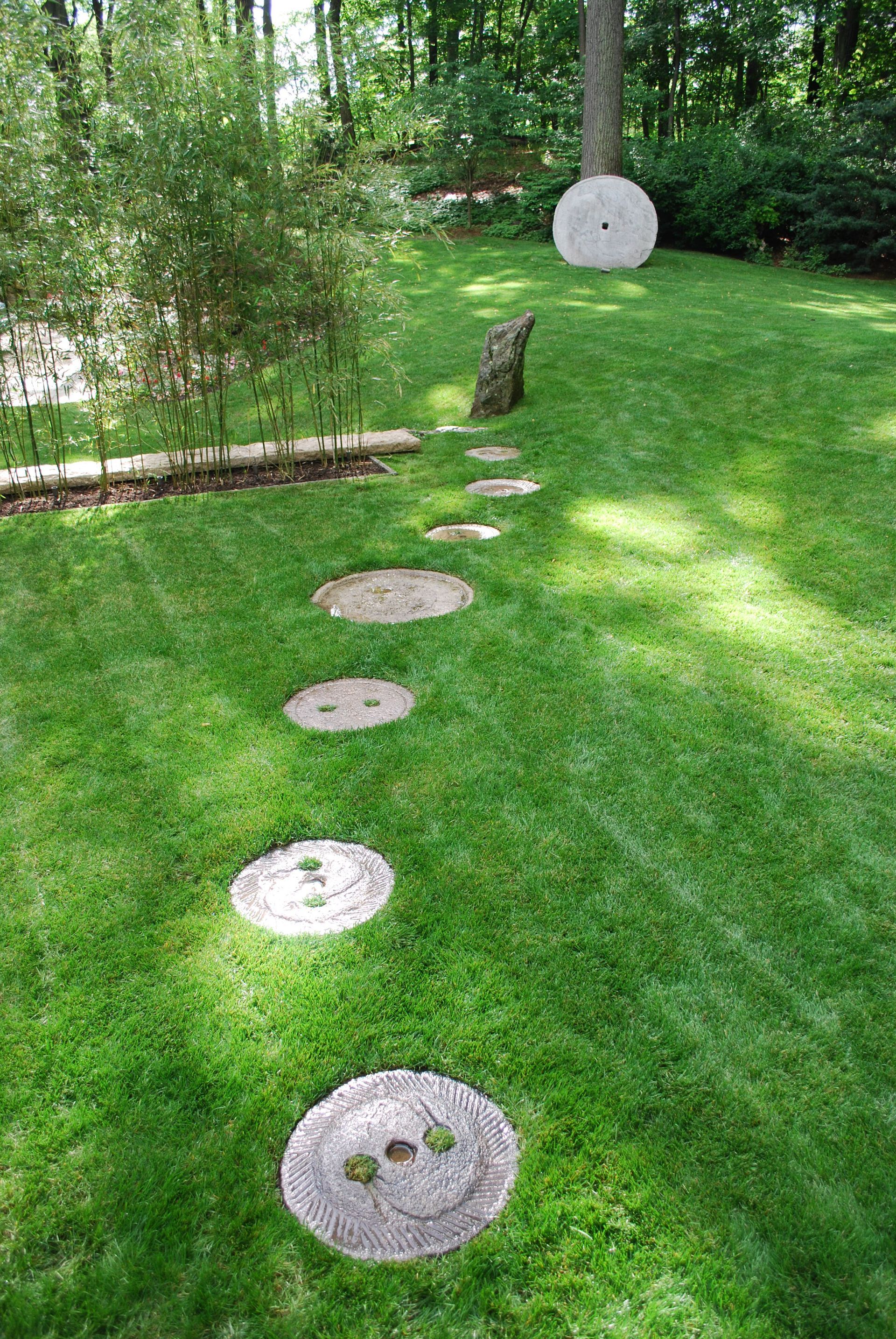 A row of stepping stones in the grass in a garden.