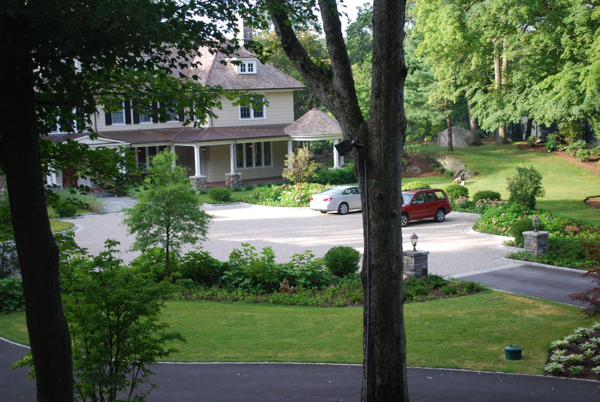 A red car is parked in front of a large house