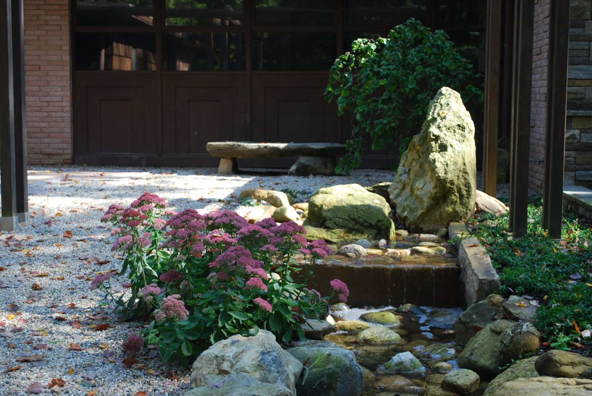 A garden with rocks and flowers in front of a garage door