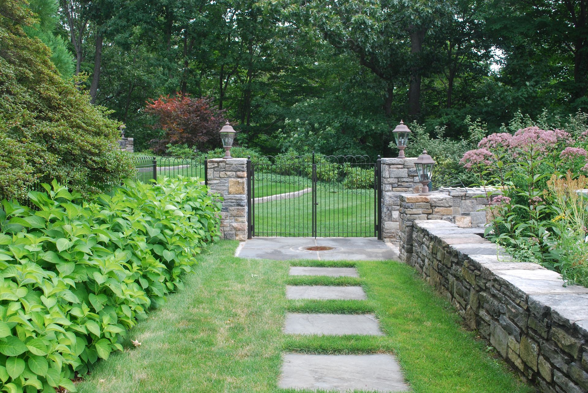 A stone walkway leading to a gate in a garden