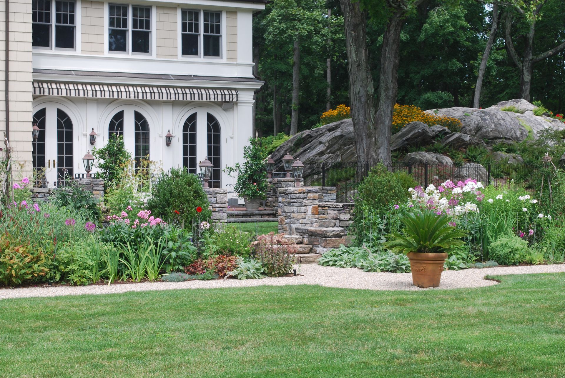 A large white house is surrounded by a lush green garden