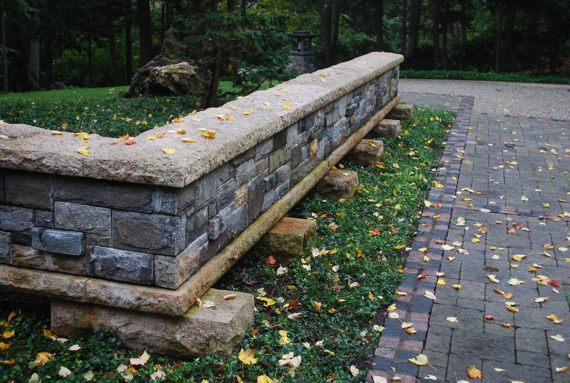 A stone wall with a brick walkway in the background