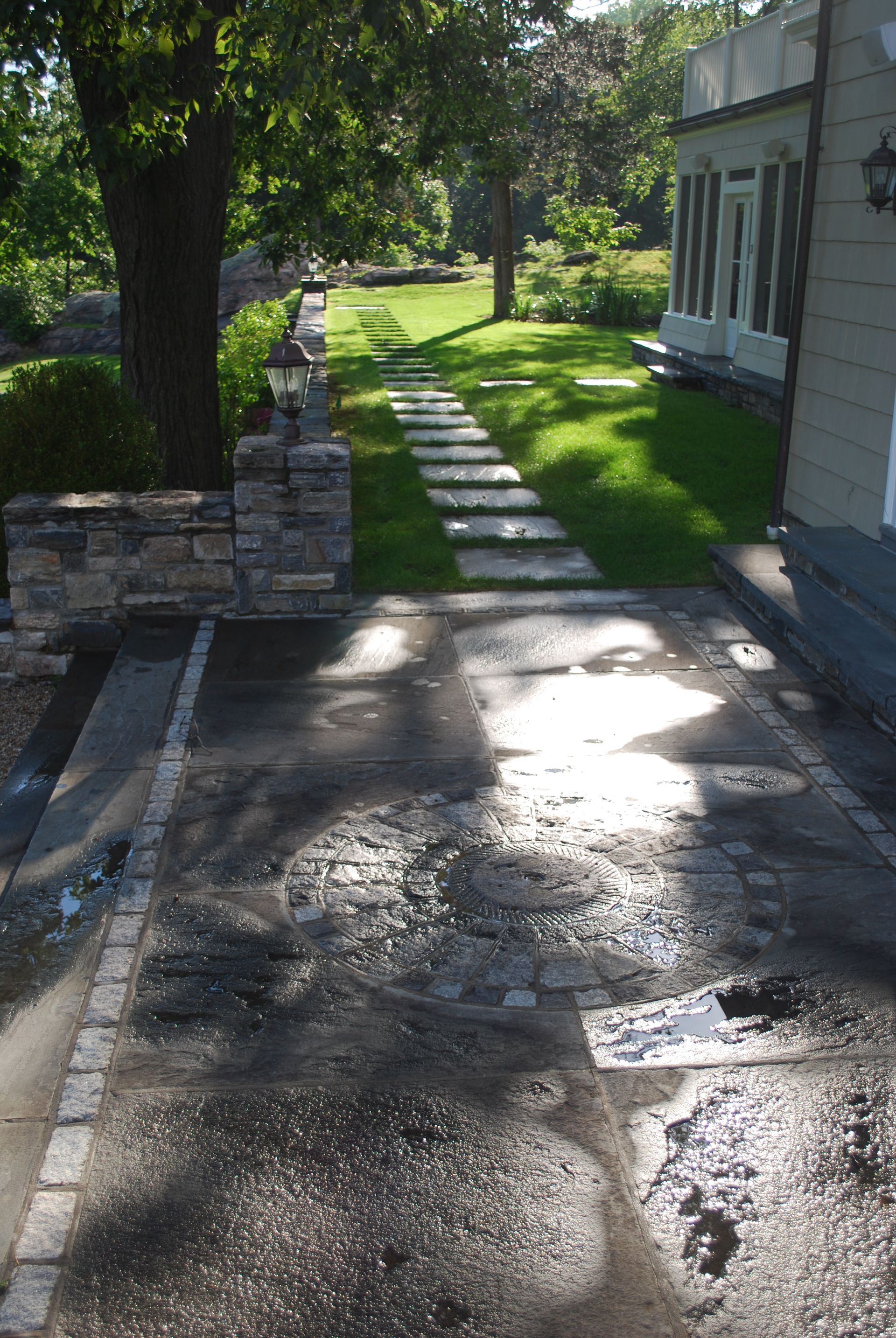 A walkway leading to a house with a stone wall