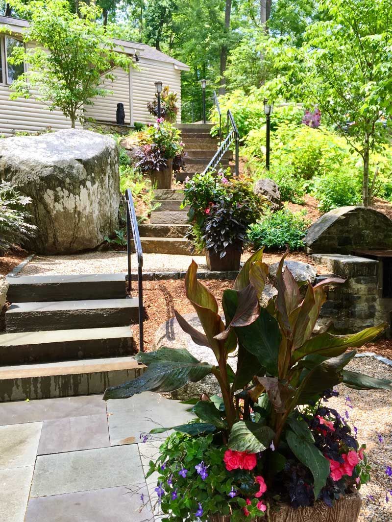 A garden with stairs and flowers in front of a house.