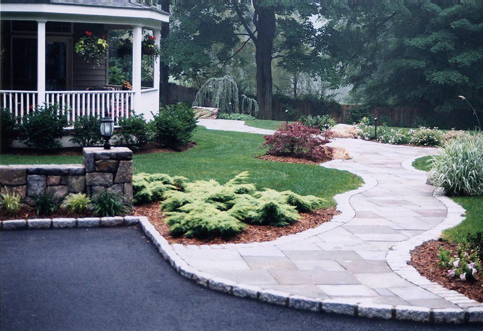 A stone walkway leads to a house with a porch