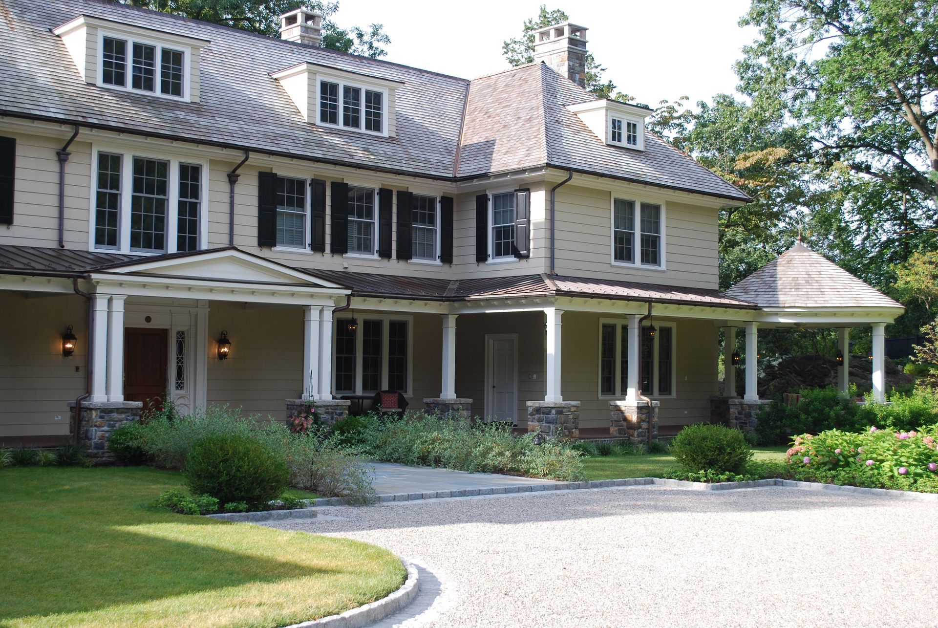 A large house with a large porch and a gravel driveway