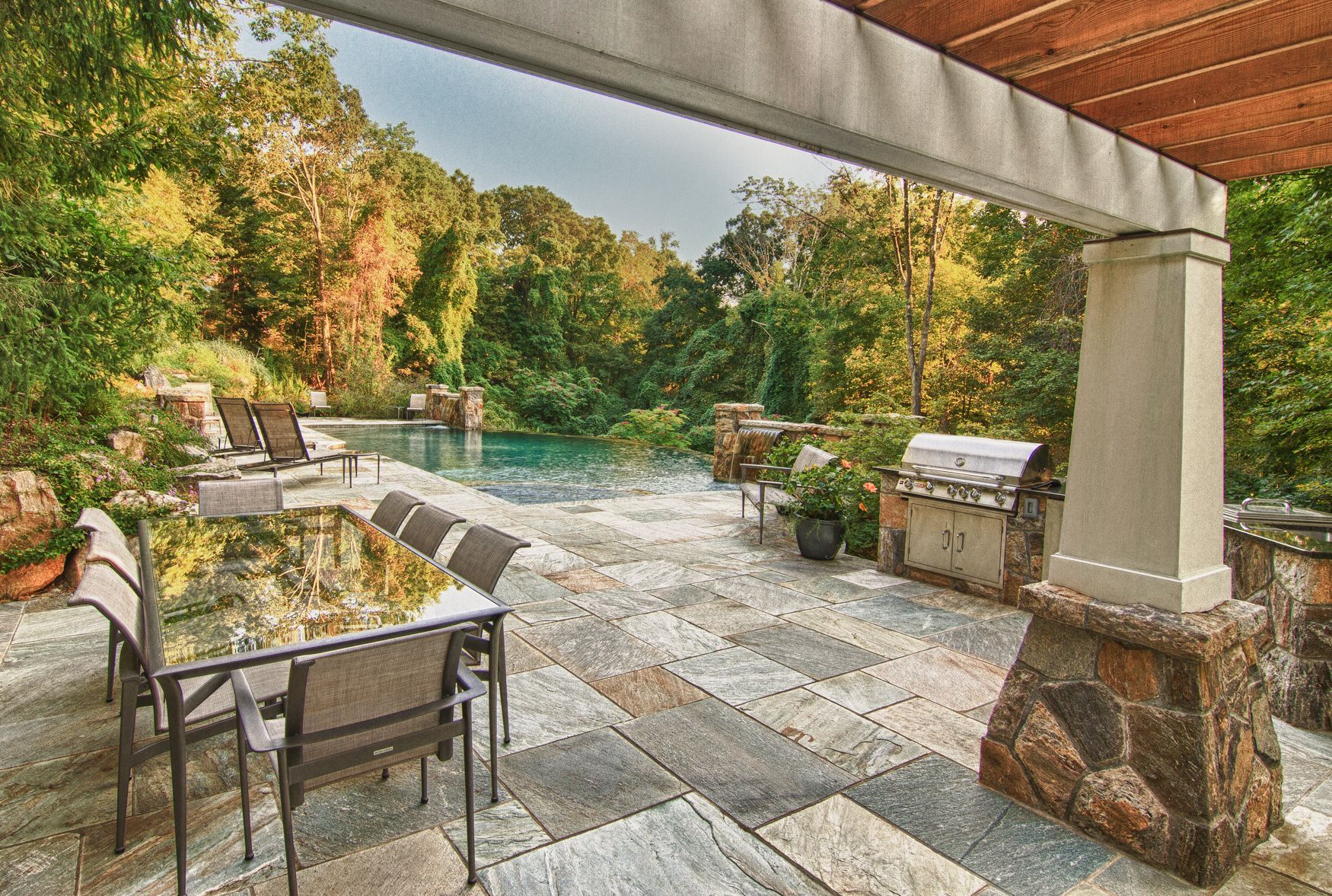 There is a patio with a table and chairs and a grill.