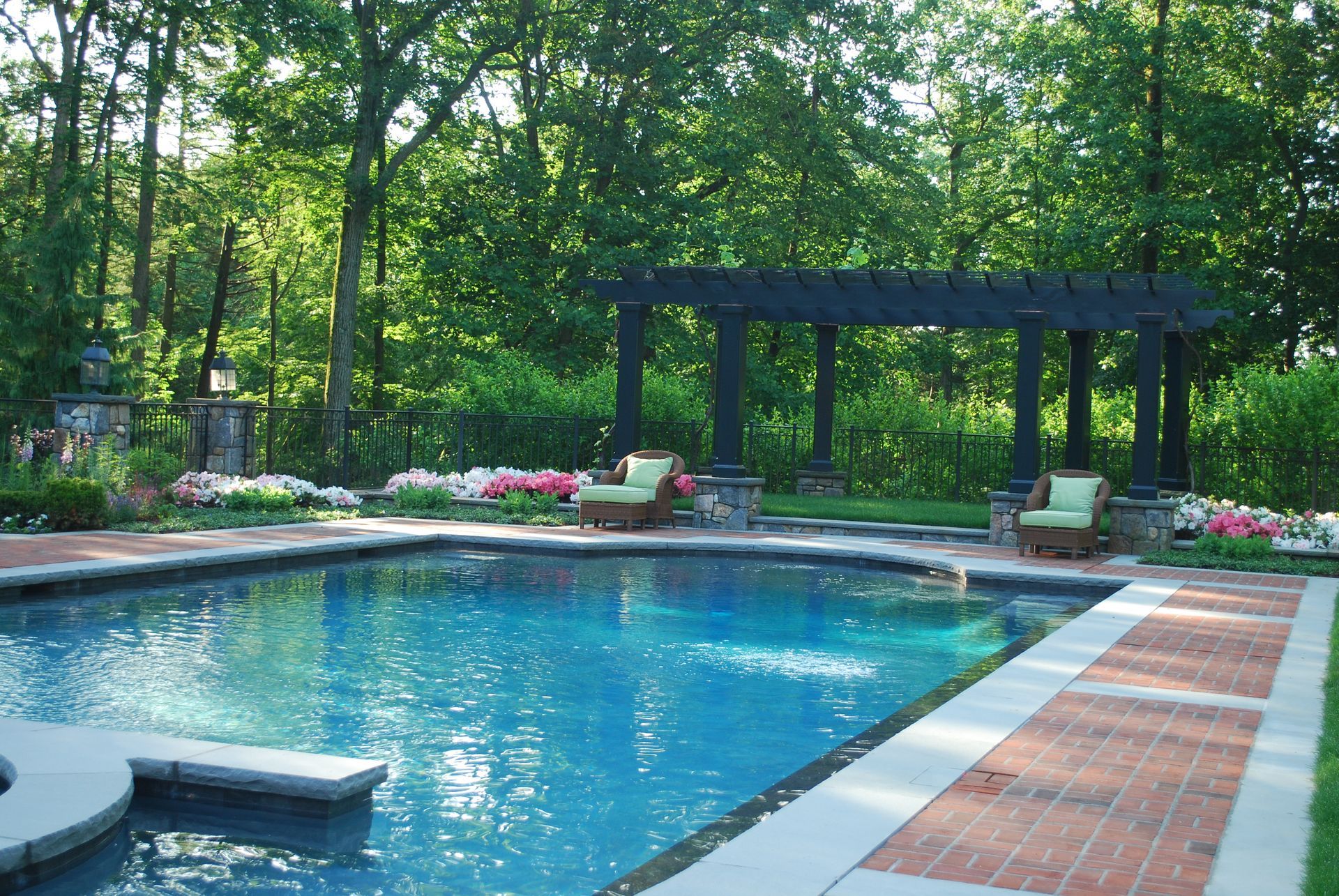 A large swimming pool with a pergola in the background