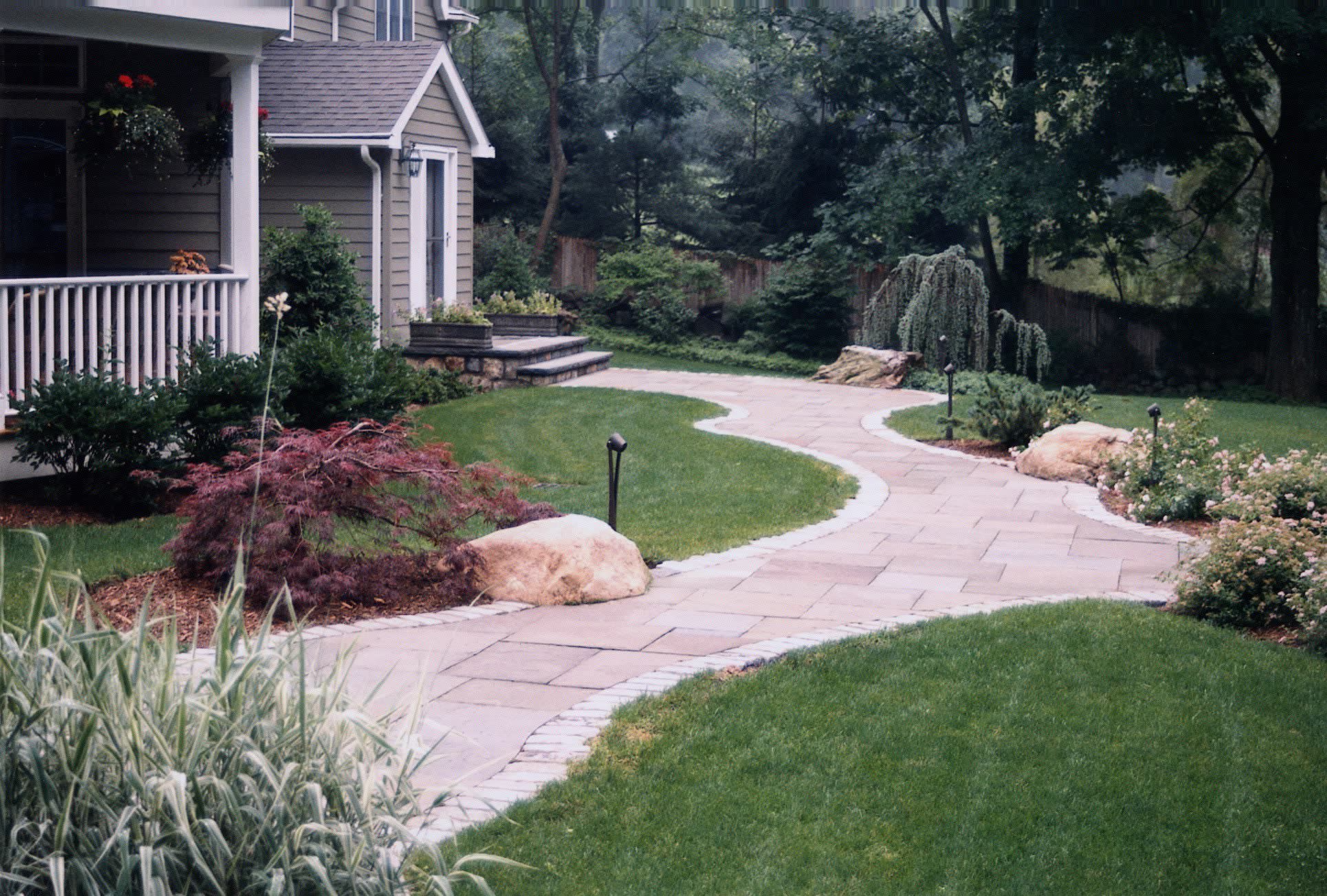 A stone walkway leading to a house with a porch