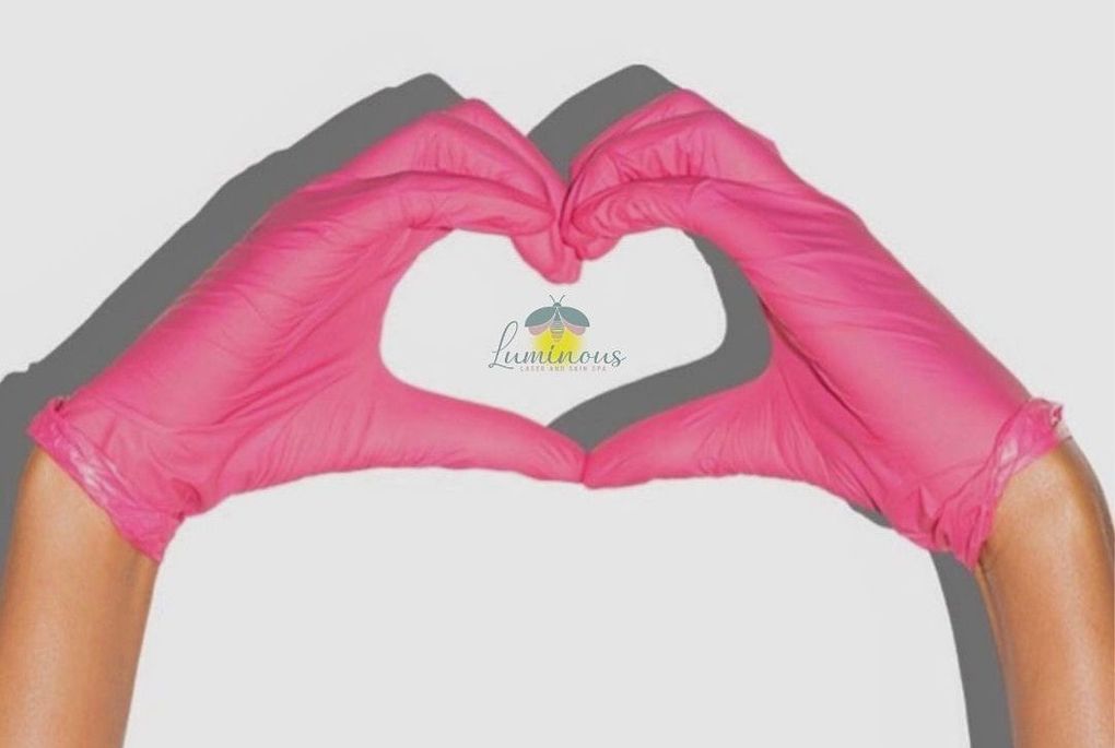 A person wearing pink gloves is making a heart shape with their hands