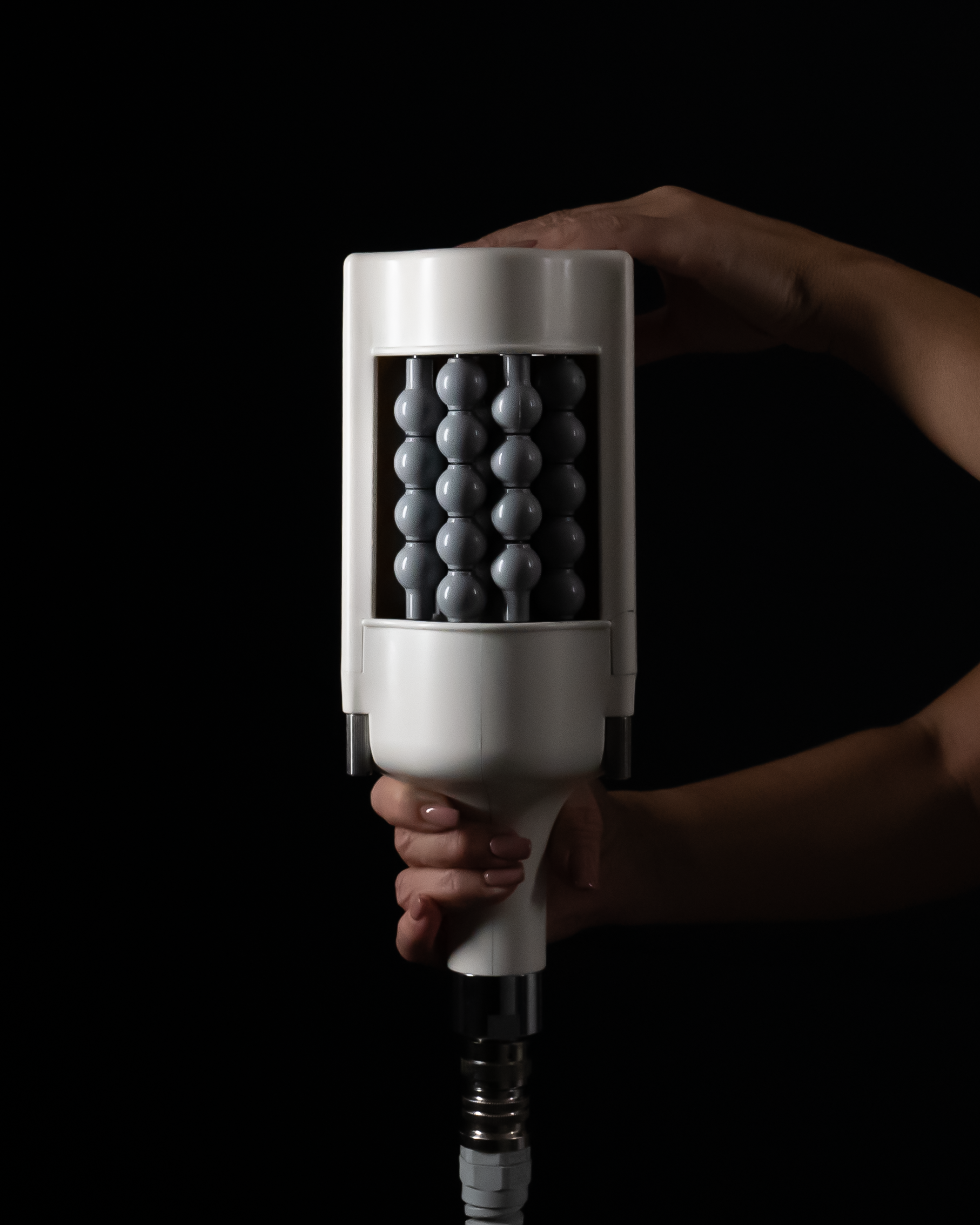 A person is holding a white object in their hand against a black background.