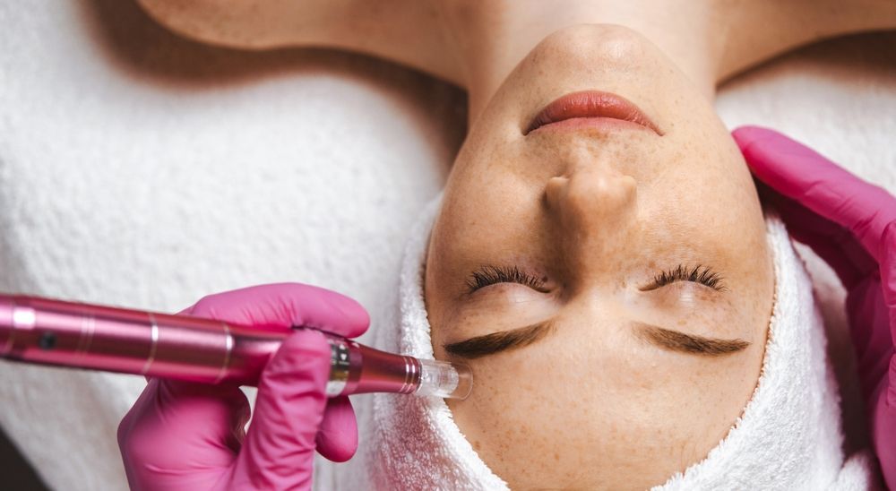 Spa treatment with gloved hands using a facial device on a reclining person's face