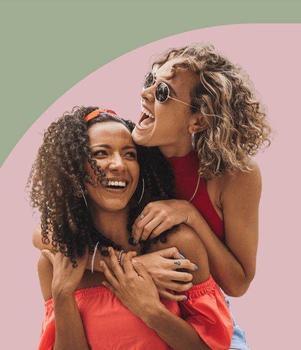 Two women are hugging each other and laughing.