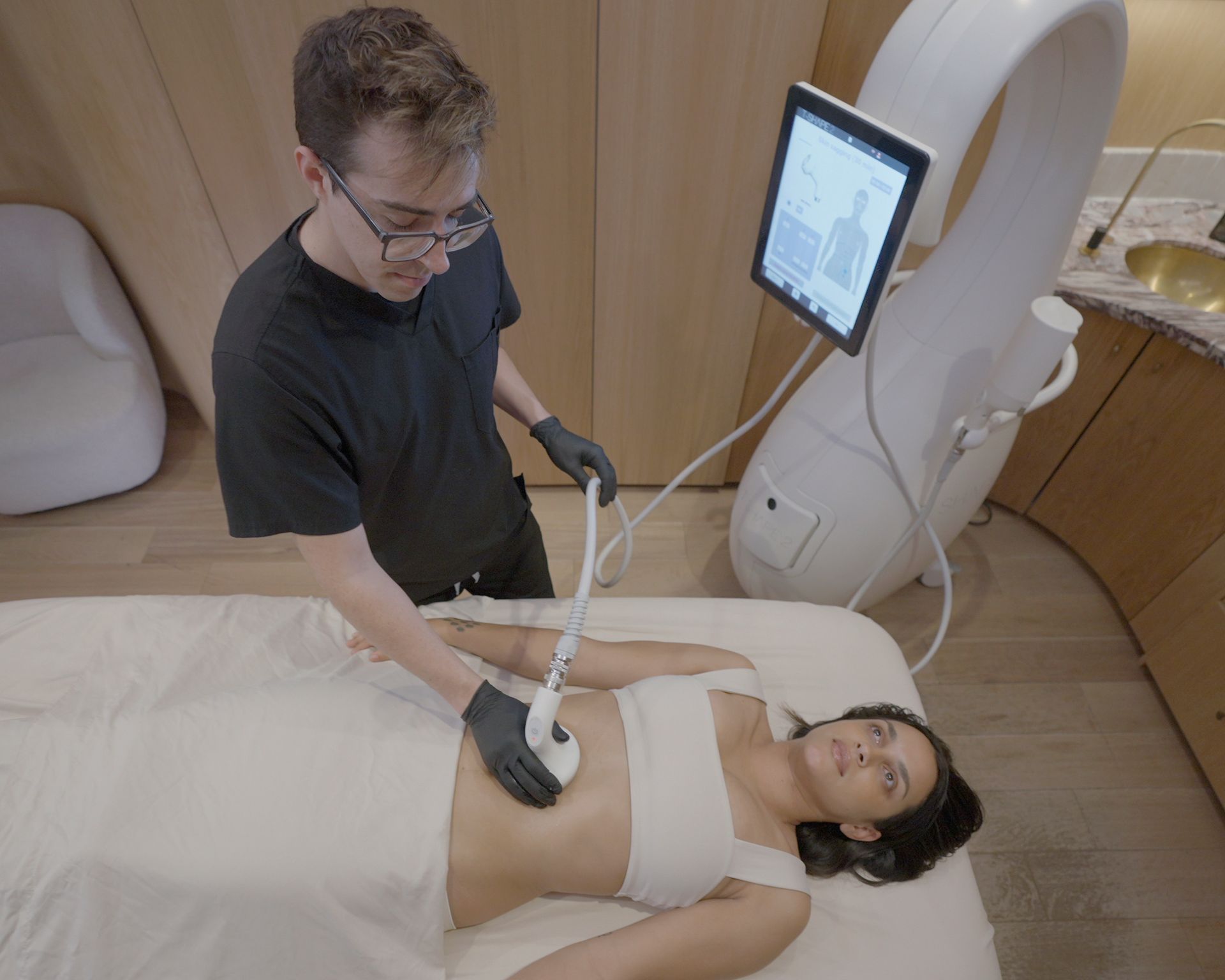 A woman is laying on a bed getting a treatment from a man.