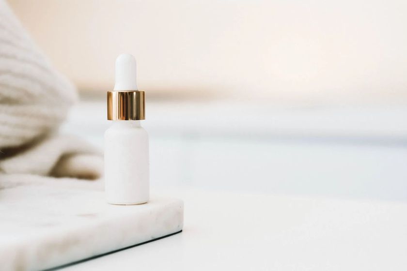 A white bottle with a gold cap is sitting on a marble cutting board.