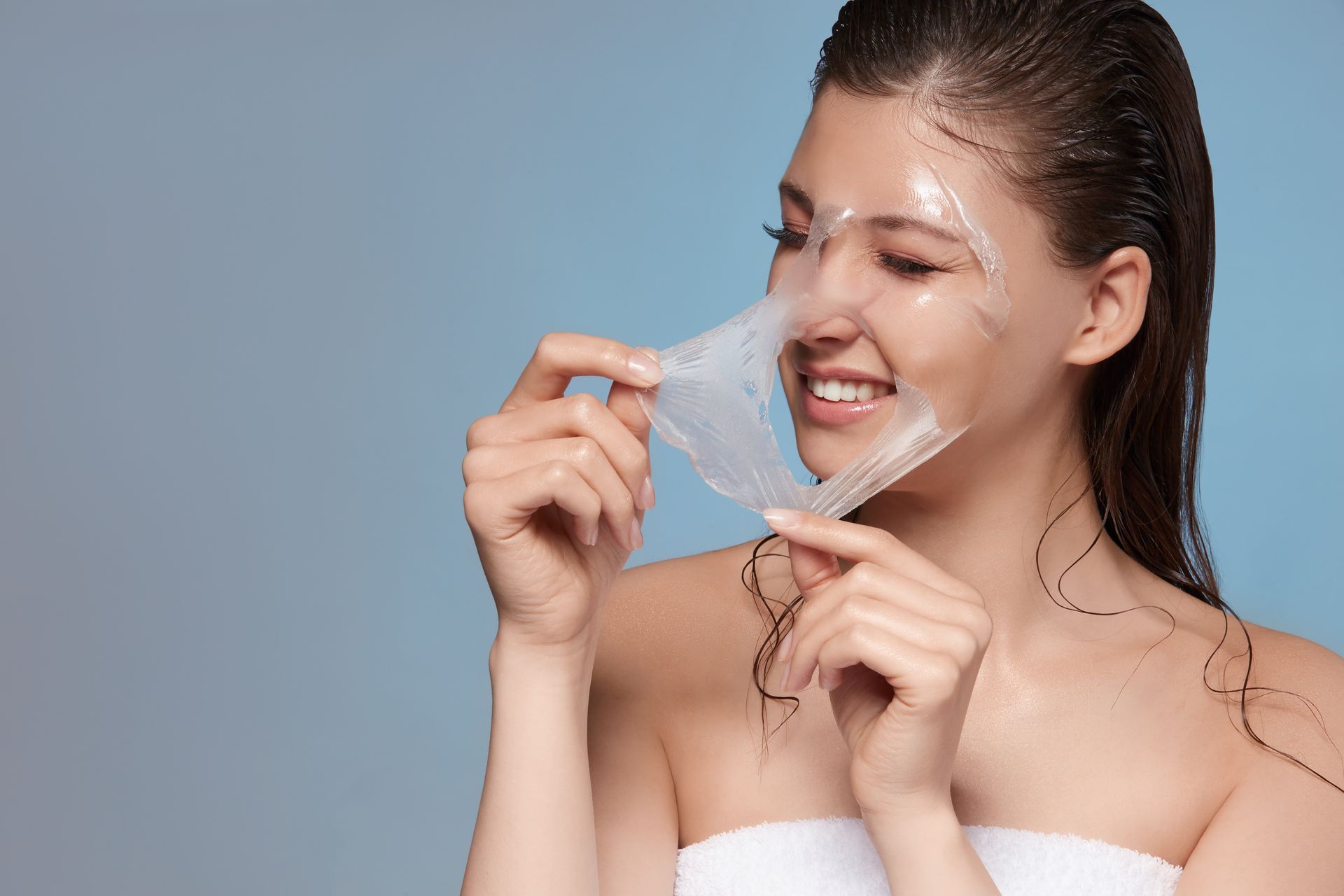 A woman is peeling off a plastic mask from her face.
