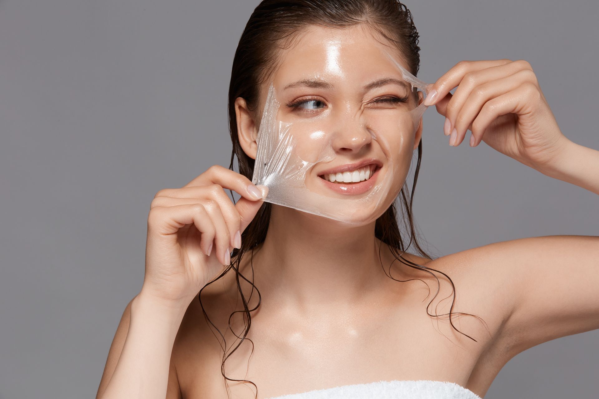 A woman is peeling off a mask from her face.