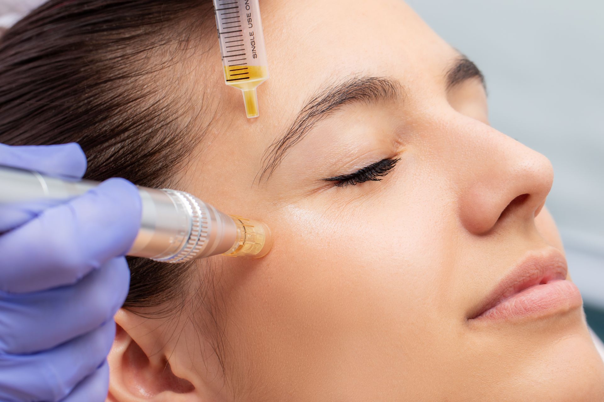 A woman is getting a facial treatment with a syringe.