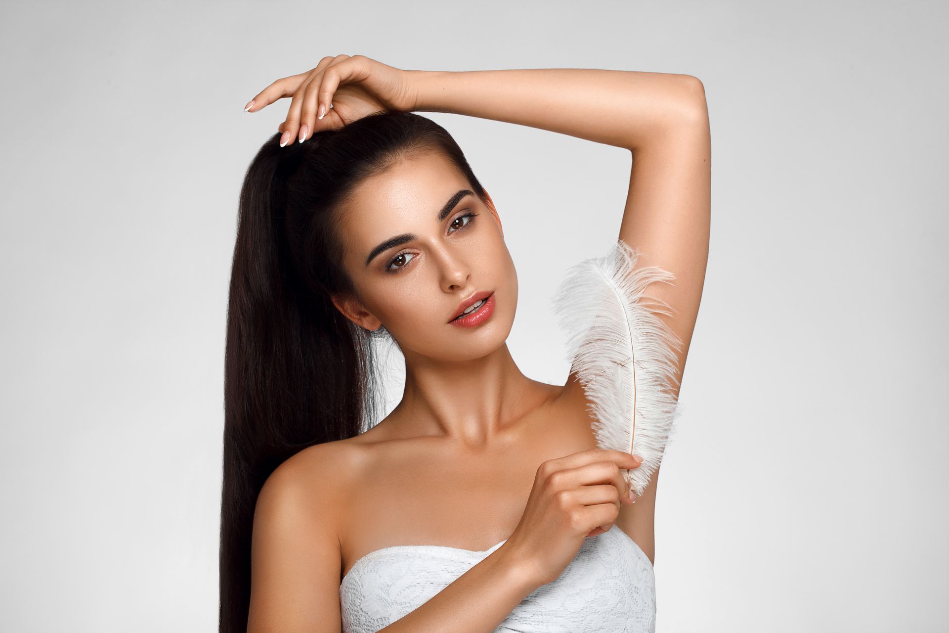 A woman is holding a white feather on her arm.