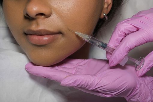 A woman is getting a botox injection in her forehead.