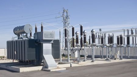 A large industrial electrical transformer and high-voltage switchgear equipment at an outdoor substation.
