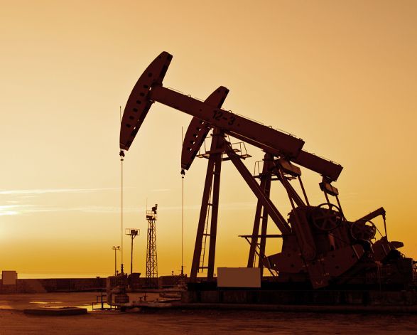 Two technicians in hard hats inspect electrical panel, one using a laptop in a control room.