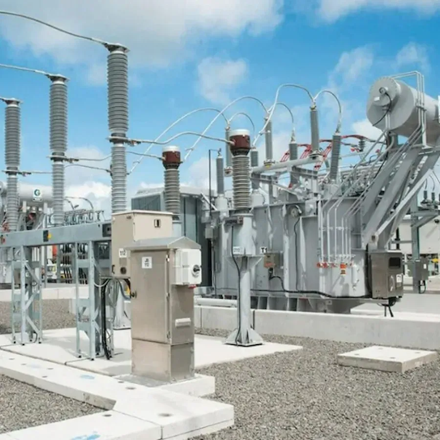 Electrical substation with high-voltage equipment, wires, and insulators against a blue sky.