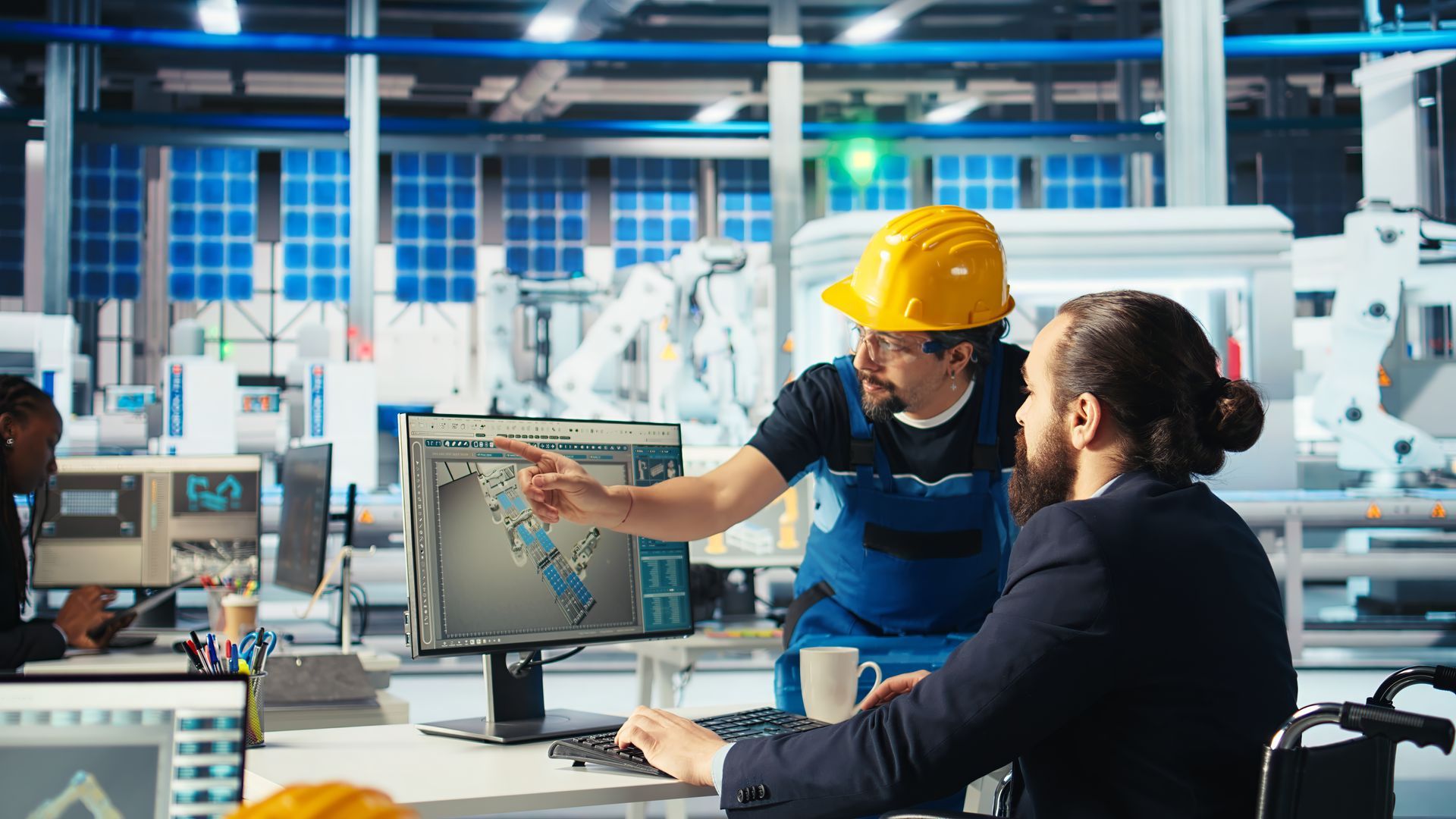 Two men are looking at a computer screen in a factory.