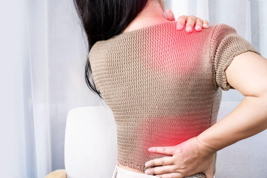 Woman smiling, seated outdoors on wooden steps, wearing denim shirt and jeans.