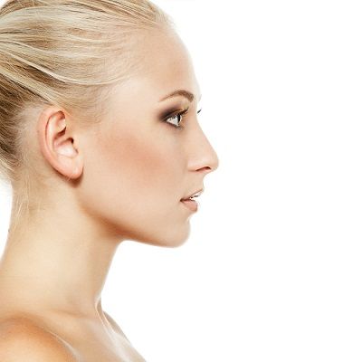 Woman's profile view with blonde hair up, lightly made-up face, looking right against a white background.