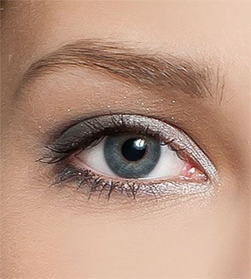 Close-up of a blue eye with silver eyeshadow and groomed brown eyebrow.